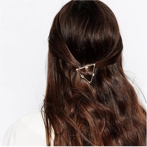 Elegant gold metal triangle arrow hair clip styled in long brown wavy hair