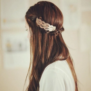Elegant gold hollow leaf hair clip worn on brunette hair in a cozy indoor setting