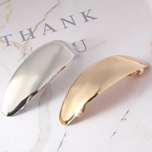 Detail of polished gold and silver metal hair clips set on white marble surface
