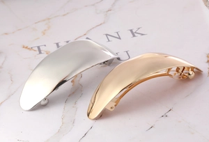 Close-up of polished silver and gold large metal hair clips on marble card