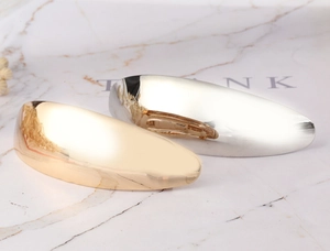 Close-up of polished gold and silver metallic hair clips on a marble surface