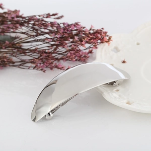 Polished silver metal hair clip with a minimalist curved design on a decorative background