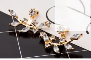 Close-up of gold plated crystal leaf earrings with marquise-cut stones in a branch design