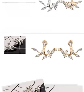 Close-up of leaf-shaped ear cuffs with marquise zircons in silver and gold plating