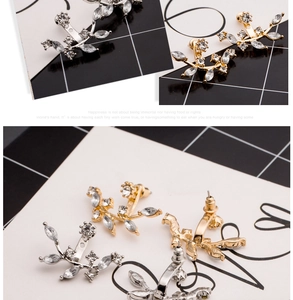 Macro detail of leaf-shaped crystal ear jackets in gold and silver finish with rhinestones