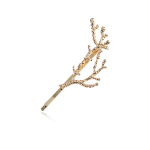 Macro detail of golden branch-shaped hair clip with natural bark texture and mirror reflection