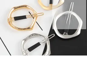 Detail view of faceted irregular circular hair clips in gold and silver finishes
