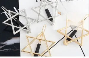 Set of gold and silver hexagram star hair clips with non-slip grips on marble surface