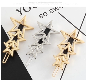 Detail of three metal star-shaped hollow hair clips in gold and silver finish