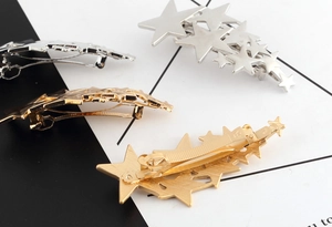 Close-up of metallic star hair clips showing silver, gold, and grey finishes