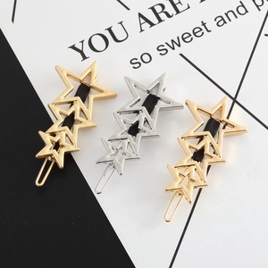 Detail view of three hollow star-shaped metal hair clips in gold and silver finishes