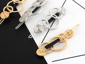 Detail showing geometric triple loop metal hair clips in gold and silver finishes