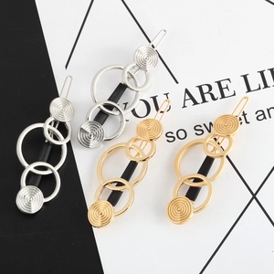 Detail of geometric hair clips featuring triple metal rings and spiral textured discs