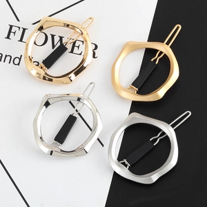 Detail of geometric hair clips in gold and silver showing matte and polished textures