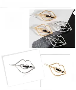 Detail of lip-shaped cutout metal hair clips in polished gold and silver finishes