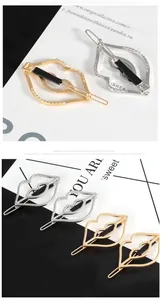 Close-up of gold and silver hollowed lip-shaped hair clips with snap closure