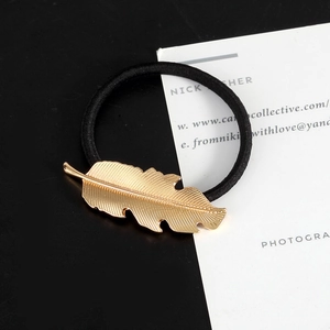 Classic black elastic hair tie featuring a detailed golden metal leaf pendant accessory
