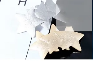 Detail of linked star hair clips in champagne gold and silver with matte texture