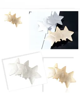 Detail view of interlocking pentagram hair clips in matte gold and silver metal finish