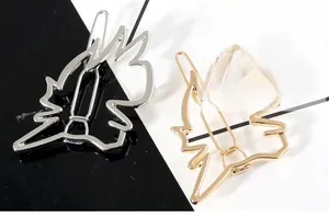 Detail view of hollow horse head metal hair clips in polished gold and silver finish