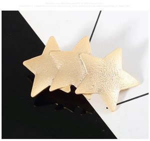 Macro view of matte gold linked star hair clip with refined brushed metal texture