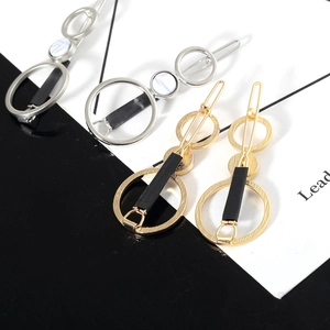 Détail de barrettes géométriques à trois anneaux avec incrustation de marbre doré et argent