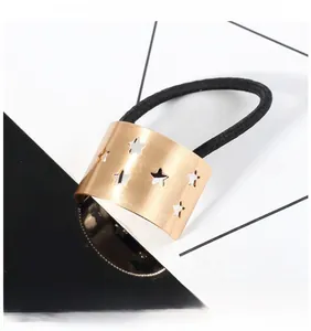 Détail de l'élastique à cheveux en métal doré avec étoile ajourée et cordon noir
