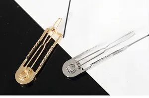 Detail view of geometric hollow hairpins in gold and silver finish with wave texture