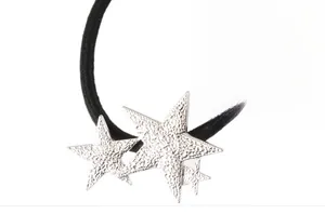 Detailed macro view of black elastic hair tie with hammered silver star charms