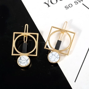 Detailed macro view of gold geometric hair clips with white marble stone and black bars