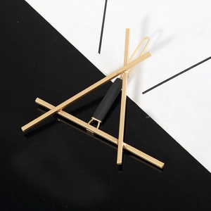 Detail of a geometric gold metal hair clip with a stylish black matte cylinder accent