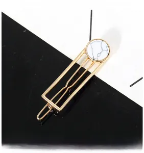 Detailed view of golden rectangular geometric hair clip with white marble texture stone