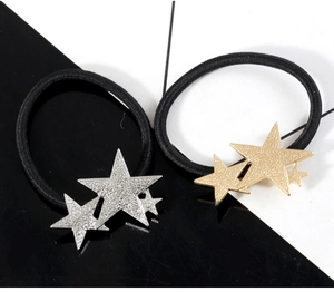 Close-up of triple layered metallic star charms on black elastic hair bands in gold and silver