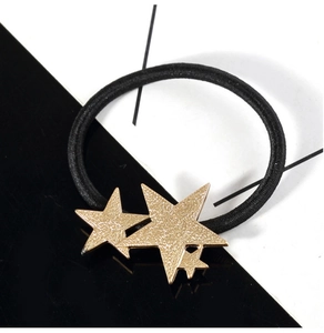 Detail of golden textured stars on black elastic hair tie with artistic background