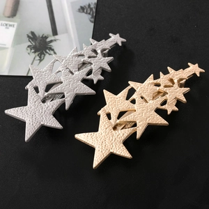Detail of gold and silver star hair clips with hammer-textured finish and alligator grip
