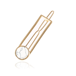 Golden hollow geometric hair clip with white turquoise marble stone inlay on white background