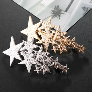 Close-up of gold and silver star hair clips with unique hammered metal texture finish