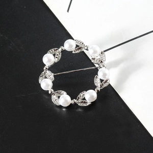 Élégante broche couronne de feuilles argentées avec perles blanches sur fond noir et blanc