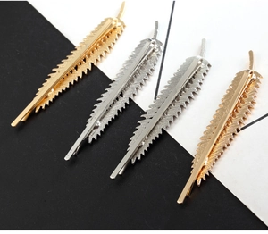 Detailed view of four leaf-shaped zinc alloy hair clips in gold and silver finishes