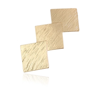 Macro detail of overlapping geometric gold squares with a fine brushed metal texture finish