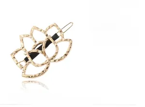 Detail view of a hollow rose hairpin in gold finish with hammered texture and black clip