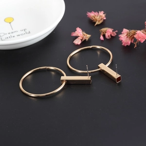 Boucles d'oreilles géométriques dorées avec pendentifs cercle et rectangle sur fond noir