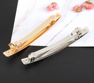 Detail view of gold and silver rectangle hair clips with textured brushed metal finish