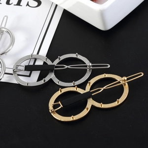 Macro view of double-circle 8-shaped metal hair clip with spike edges in gold and silver