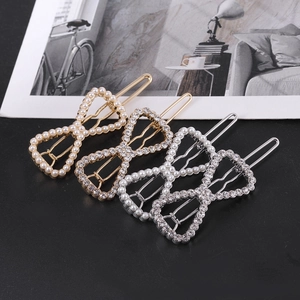 Détail de pinces à cheveux en forme de nœud ajouré avec perles et strass en doré et argenté