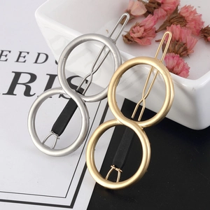 Detail of minimalist gold and silver figure-eight alloy hair clips on a ceramic plate
