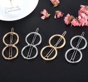 Detail view of four infinity shaped hair clips in gold and silver matte and glossy finishes