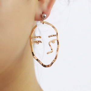 Macro shot of minimalist gold face outline earrings with silver stud on female model ear