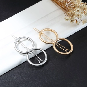 Detail of gold and silver double circle geometric hair clips on a minimalist background