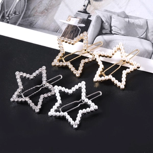 Detailed close-up of hollow star hair clips with pearls and rhinestones on black surface